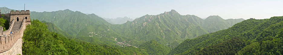 The iconic watchtowers and ramparts of the Great Wall of China cresting the lush green mountain ridges and steep valley passes of Northern China at Mutianyu outside Beijing. ProPhoto RGB profile for maximum color fidelity and gamut.