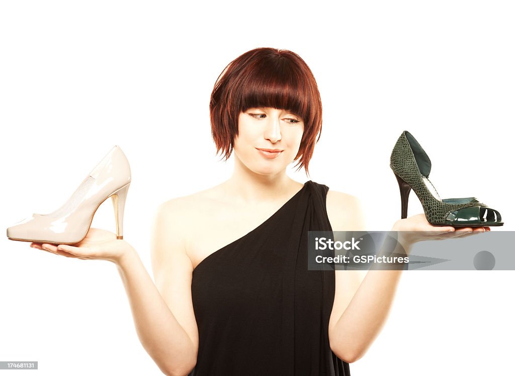 Joven mujer tratando de elegir entre dos pares de zapatos - Foto de stock de 20 a 29 años libre de derechos