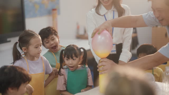 Cheerful Elementary Schoolgirls Conducting a Science Experiment in Classroom. Kindergarten. Back to School. Education.