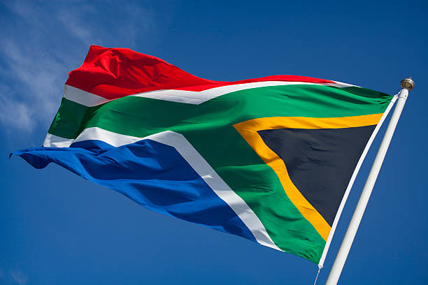 Flag of South Africa blowing in wind against blue sky South African flag waving in the wind. south africa flag stock pictures, royalty-free photos & images