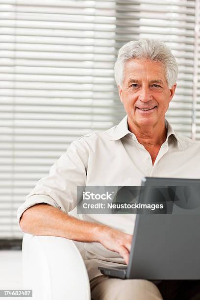 Photo libre de droit de Heureux Senior Homme Assis Avec Un Ordinateur Portable banque d'images et plus d'images libres de droit de 60-64 ans