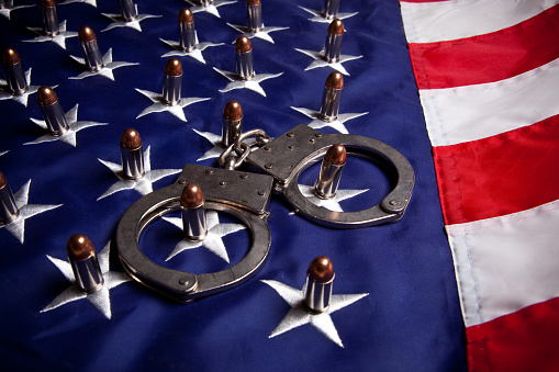 Handcuffs and bullets sit on an American flag.