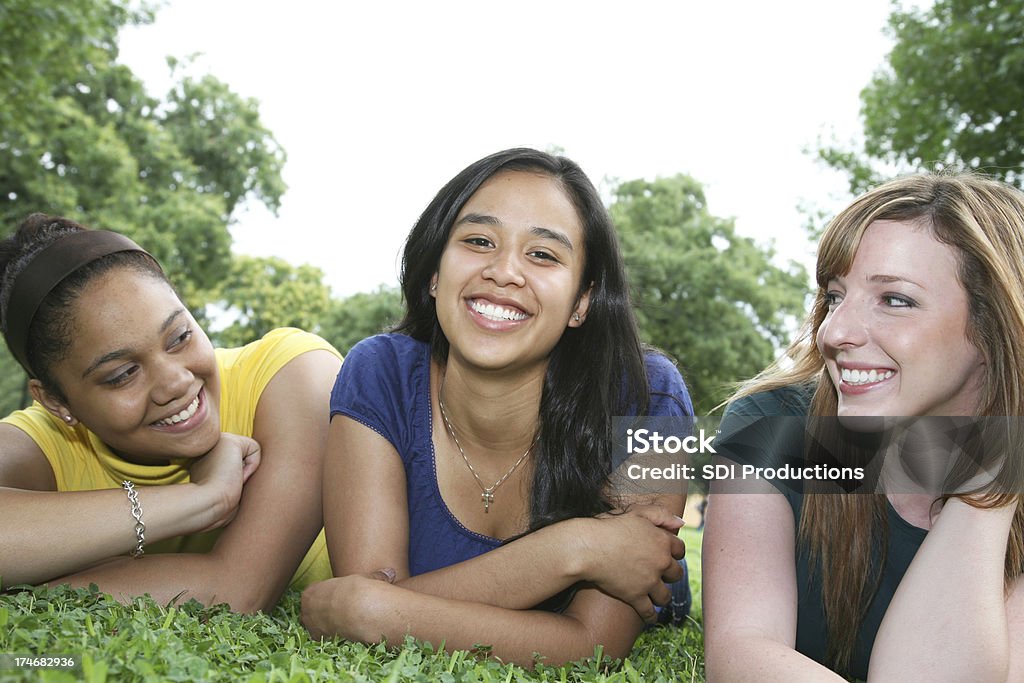Diverso grupo de sonriente mujer amigos en pasto colocación - Foto de stock de 18-19 años libre de derechos