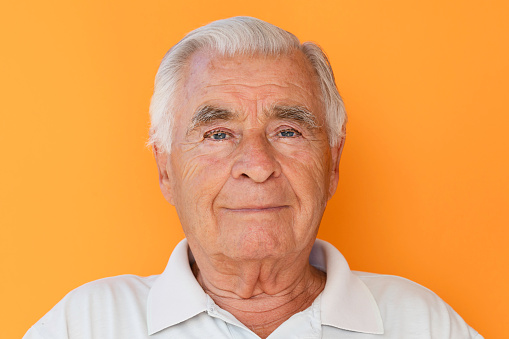 Senior man portrait in  front of orange colored   background.