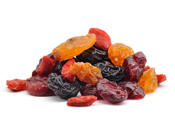 "A close up shot of a pile of dried bluberries, cherries, cranberries, goji and raisins isolated on white."