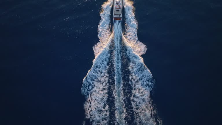 AERIAL Following a yacht cruising at sea as the sun is setting