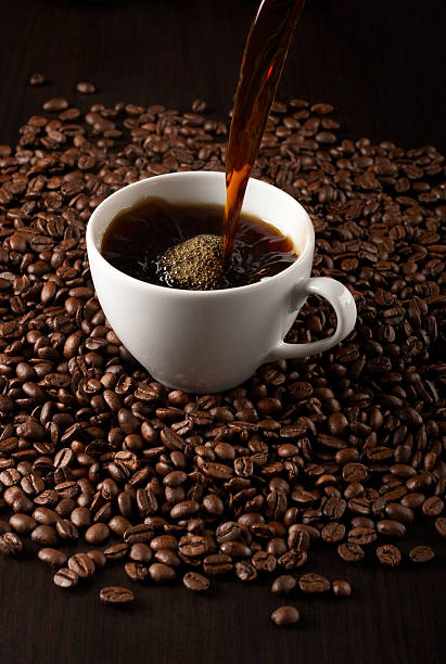 Pouring fresh coffee Pouring coffee into cup on background of coffee beans. black coffee stock pictures, royalty-free photos & images