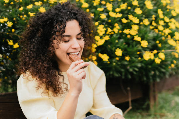 istock curly-haired woman bites chocolate bar surrounded by yellow flowers 1746854059