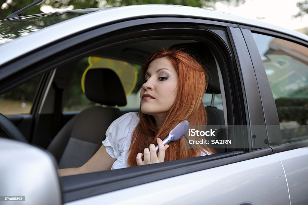 Woman in the car Beautiful young woman Brushing her hair in the car. Adult Stock Photo