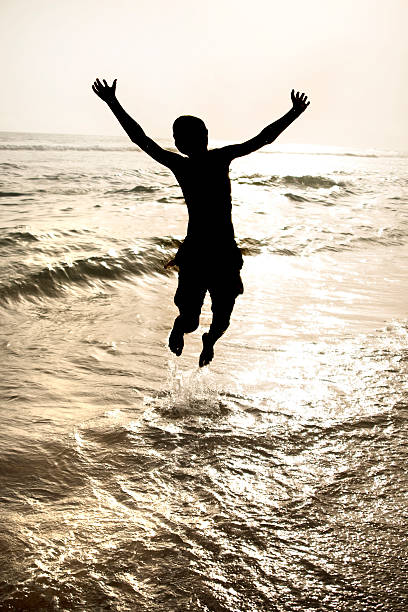 istock Silhouetted Boy Jumping in the Ocean 174686045