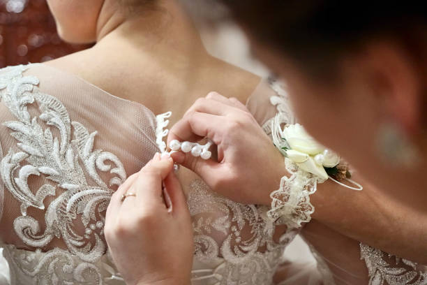 istock Girlfriends help the bride to wear a wedding dress by buttoning the back. 1746864358
