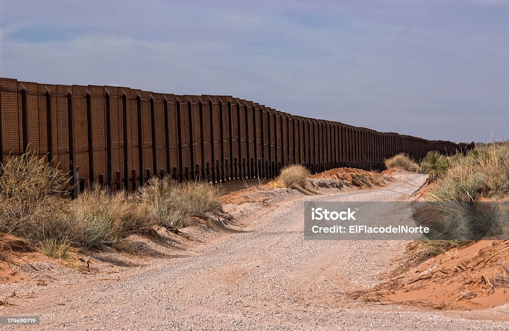 Picture of the Border Fence in New Mexico  Gravel road along the Border fence between New Mexico, USA and the northern state of Chihuahua, Mexico. International Border Barrier Stock Photo