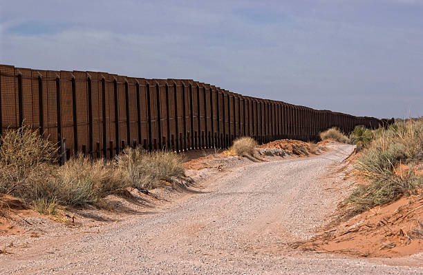 Picture of the Border Fence in New Mexico  Gravel road along the Border fence between New Mexico, USA and the northern state of Chihuahua, Mexico. barricade photos stock pictures, royalty-free photos & images