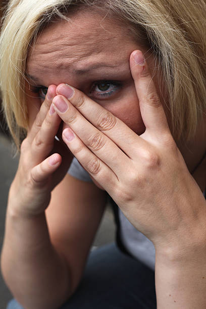 Young Woman Scared and Concerned Looking through Hands stock photo