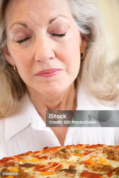 Starsza Kobieta Zapachu Pizza Z Jej Oczy Zamknięte - zdjęcia stockowe i więcej obrazów Senior