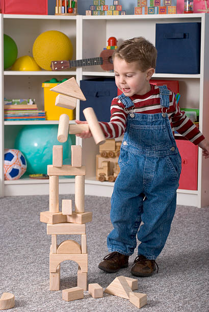 istock Boy Building With Wooden Toy Blocks Knocks Over His Tower 174692040