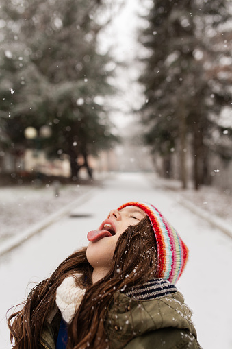 Portrait of a cheerful little girl enjoys snowing in nature