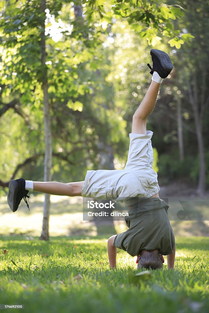 Dieci anni ragazzo cercando di fare la verticale sulla testa. - Foto stock royalty-free di 10-11 anni