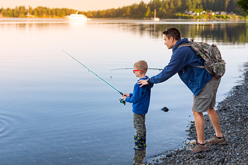 Father and son fishing together in beautiful mountain lake.