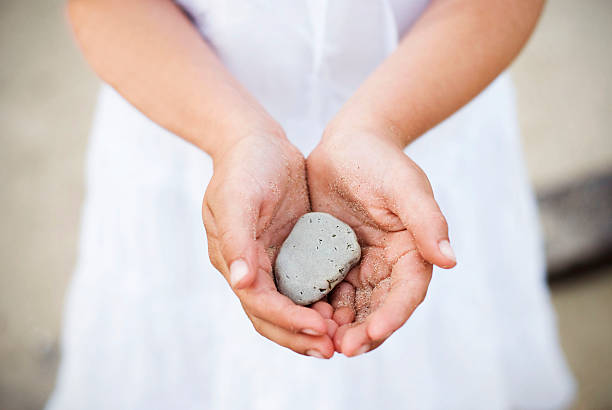 istock Young girl at beach showing rock from collection. 174693508