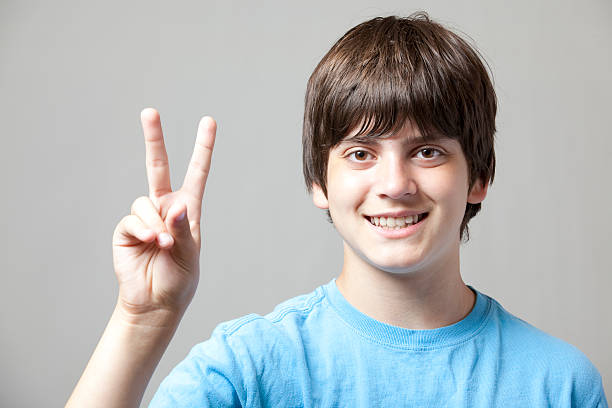 boy tiene capacidad para un máximo de dos dedos - peace sign counting child human finger fotografías e imágenes de stock