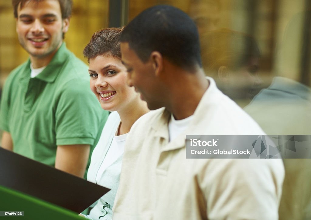 Giovani studenti seduti insieme e sorridenti - Foto stock royalty-free di 20-24 anni