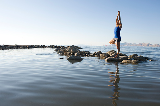 A woman doing yoga at a lake.