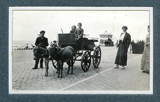 "Vintage photograph of an Edwardian family having fun at the seaside, two children sit in a donkey carriage. Knokke"