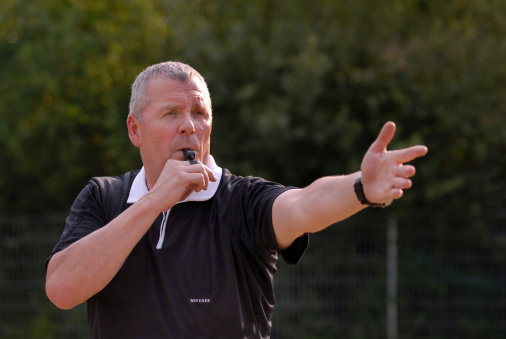 A football referee blowing his whistle.