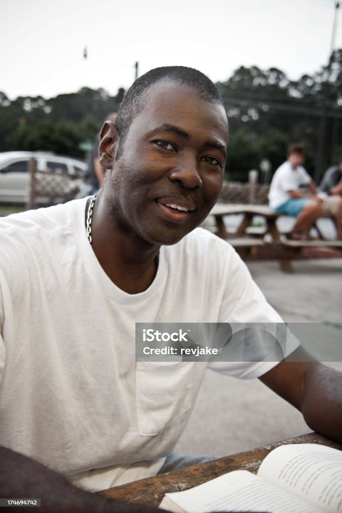 Man sits outside at a restaurant or park A man sits outside at a crowded restaurant or park. 20-29 Years Stock Photo