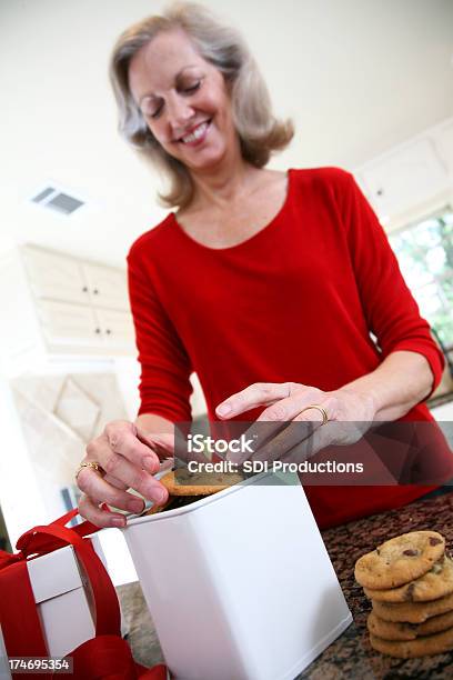 Smiling Woman Placing Chocolate Chip Cookies In Gift Box Stock Photo - Download Image Now
