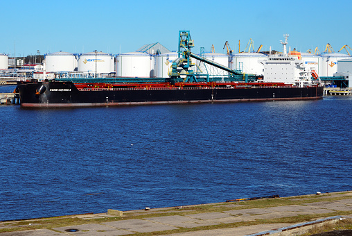 Ventspils, Latvia: Free Port of Ventspils - Konstaninos II bulk carriers (IMO 9595278) at the Baltic Coal Terminal, a closed-end coal terminal  designed by the Latvian company Ierosme, it uses closed type technologies for reducing environmental pollution - specialized coal transhipment terminal, can serve the largest vessels entering the Baltic Sea, up to 120,000 DWT - in the background the Ventbunkers bunkering terminal with a tank farm used for diesel, black fuel oil and other oil derivatives - The Port of Ventspils is a year round ice-free deep-sea port in the Latvian Baltic Sea coast. In terms of cargo throughput, it is the largest in Latvia.