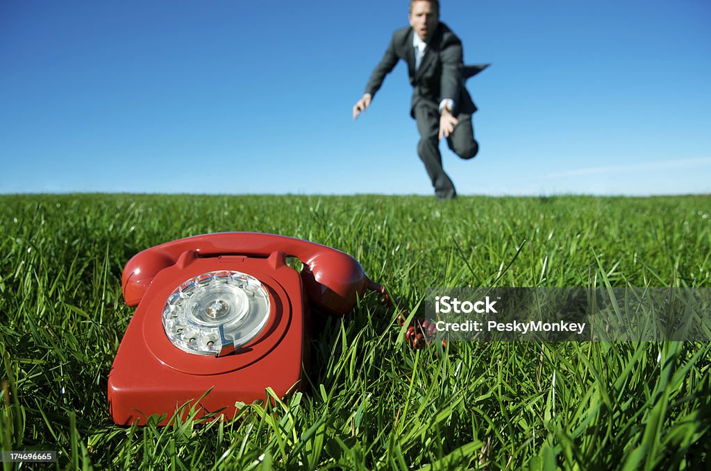 Rosso telefono di emergenza in prato con un uomo d'affari corre - Foto stock royalty-free di Affari