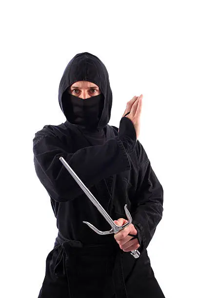 A ninja on a white background stands with one sai weapon.