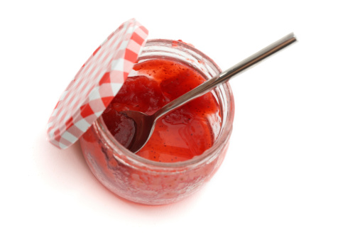 A jar of homemade strawberry jam on white background