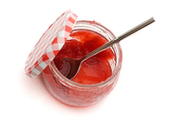 A jar of homemade strawberry jam on white background