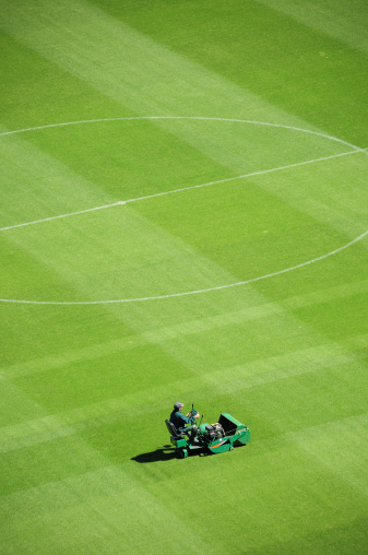 lawn mower vehicle on the playfield in a huge soccer stadium.