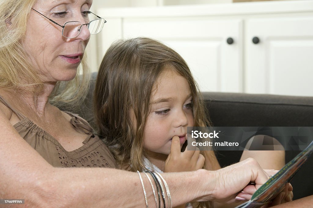 Lectura a su abuela granddaughter. - Foto de stock de 4-5 años libre de derechos