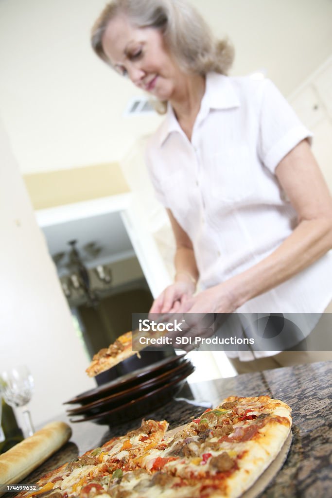 Amos de casa de colocar rebanada de Pizza en un plato - Foto de stock de 50-59 años libre de derechos