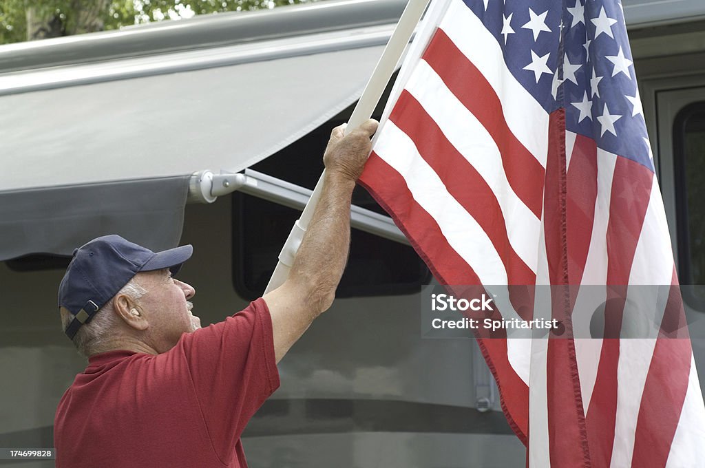 Senior alzando bandiera in campeggio Roulotte - Foto stock royalty-free di Camper