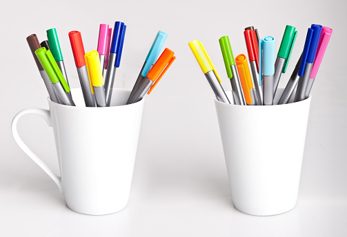 Colourful assorted felt tip pens in a white porcelain mug