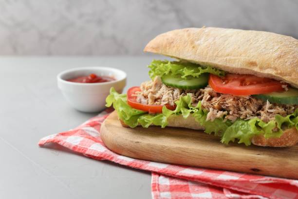 istock Delicious sandwich with tuna, vegetables and tomato sauce on light grey table, closeup. Space for text 1747013445