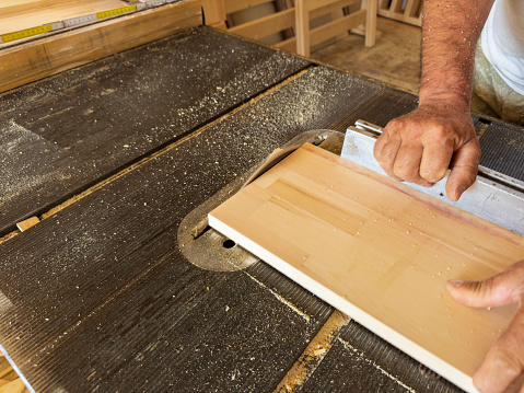 Carpenter cutting wooden boards for furniture in his workshop