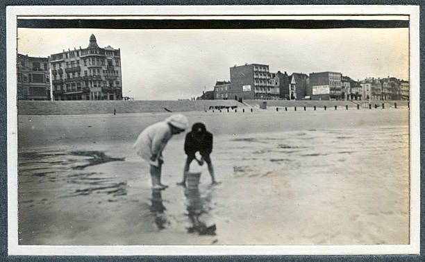 Edwardian children playing at the seaside - Old Photograph "Vintage photograph of two Edwardian children playing in the sand at the seaside. Knokke, Belgium." beach hut photos stock pictures, royalty-free photos & images