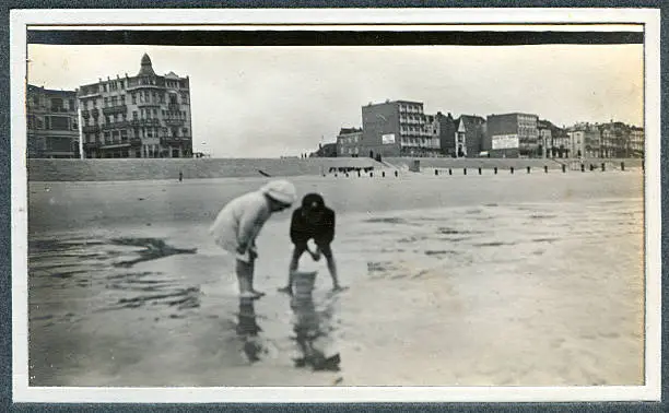 "Vintage photograph of two Edwardian children playing in the sand at the seaside. Knokke, Belgium."