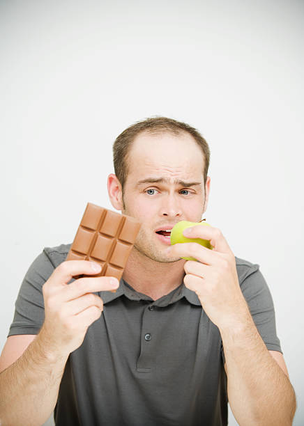 istock Diet Choice with Man holding Chocolate and Apple 174701424
