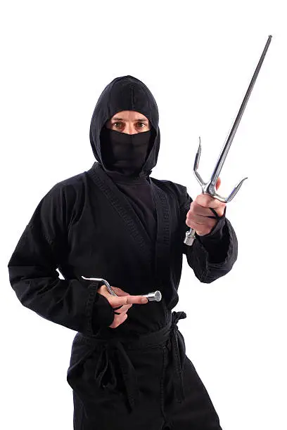 A ninja on a white background and armed with sais attacks with a one-sai strike.