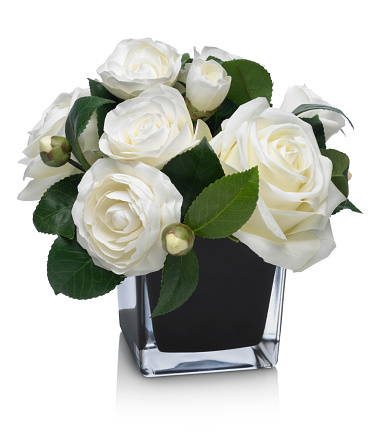 A mixed rose and camellia bouquet in a glass vase with reflection, isolated on white. The image has an embedded path to delete the reflection if desired.  Photographed on a bright white background. Extremely high quality faux flowers. 