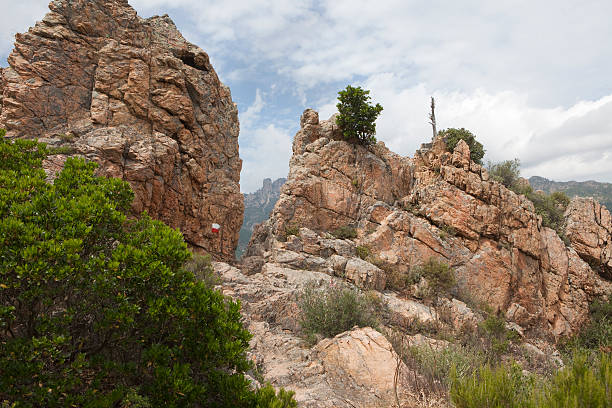 Crevice on the famous GR 20 hiking trail in Corsica. The white/red painting indicates the GR 20 trail. The crevice has to be passed. This image taken around 1 hour from Conca at a point called Bocca d'Usciolu. In the background part of the Bavella mountain range.