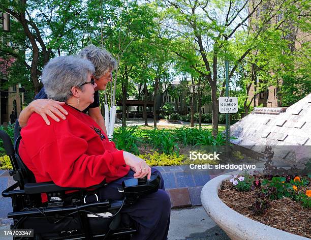 A Woman In A Wheelchair Accompanied By Another Woman Stock Photo - Download Image Now